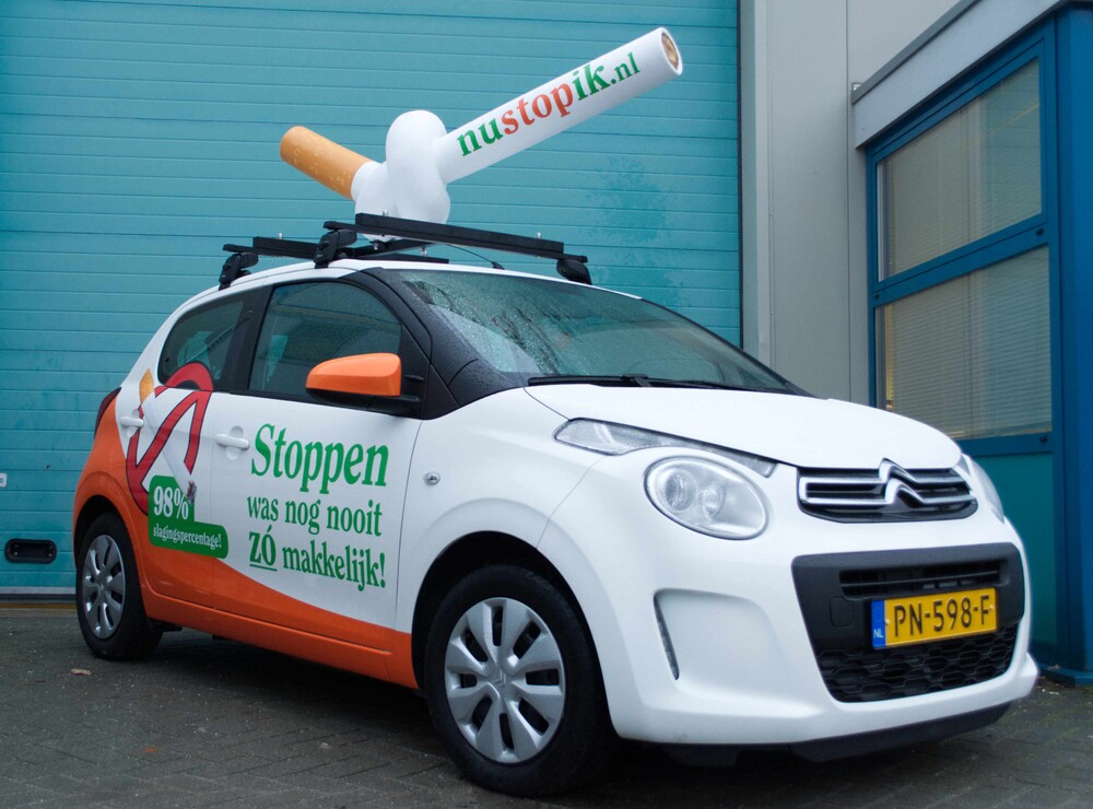 Autoreclame, solid blowup van een sigaret op autodak.