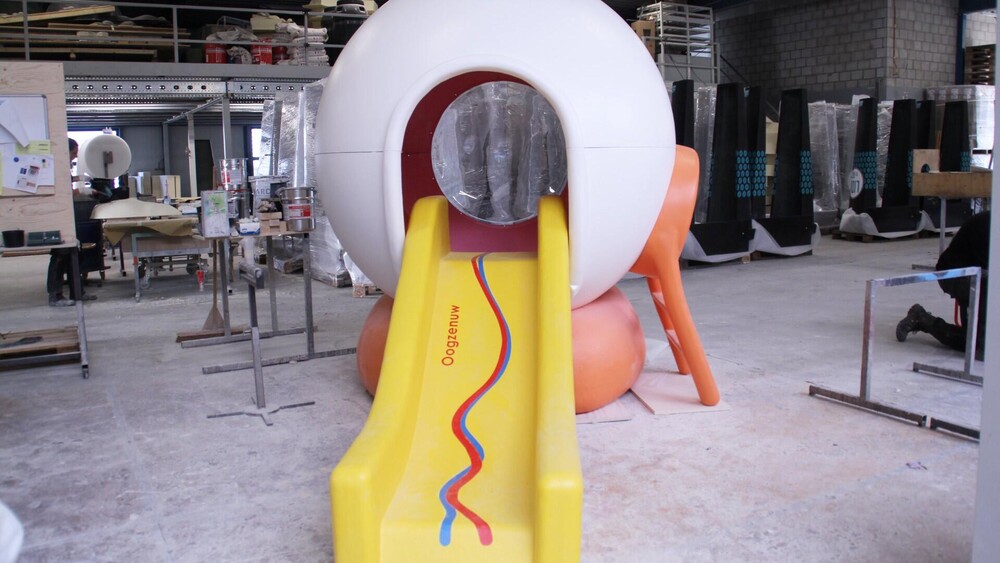 Thematisch polyester speeltoestel. Blowups ontwierp voor Bartimeus een speeloog dat bestaat uit een oogbol met de iris, (doorzichtige) pupil en een polyester glijbaan die symbool staat voor de bloedvaten die naar het oog lopen. Het speeloog heeft een diameter van 2000 mm en een hoogte van 1600 mm, het 3d-object is demontabel gemaakt zodat het toestel inpandig te verplaatsen is.