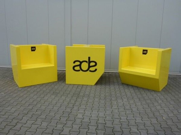 Gele bankjes voor ADE. Bankjes in de vorm van het logo.
